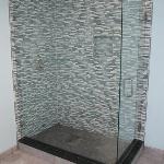 MODERN GLASS SHOWER INCLUDING GLASS TILE AND BLACK GRANITE CURB